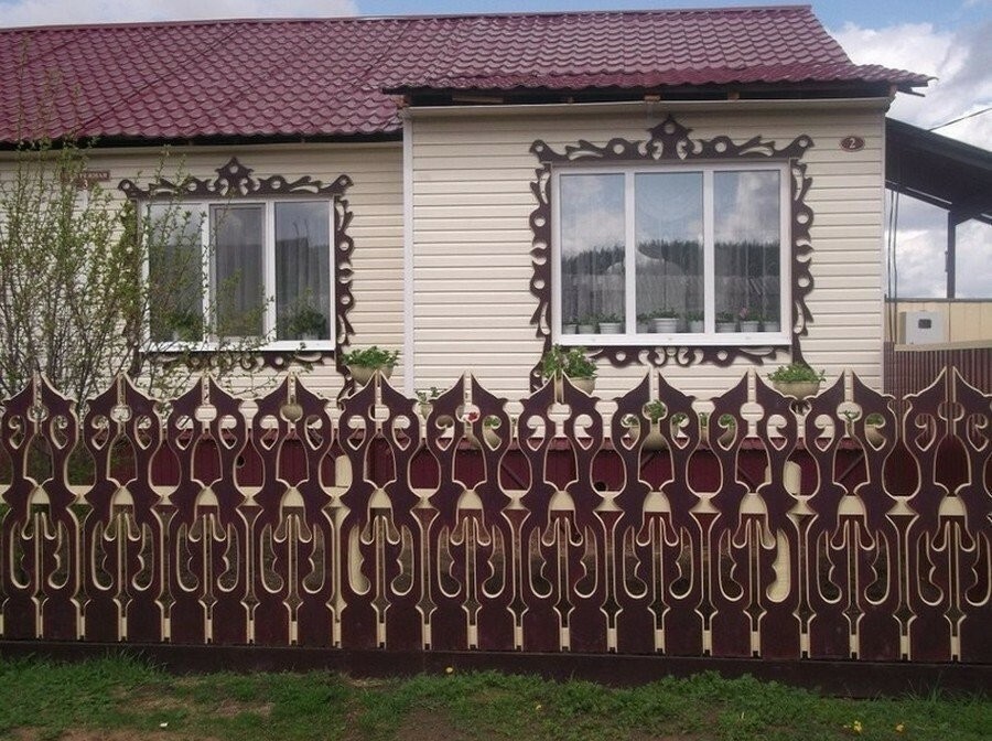 Voortuin van een landelijk huis met een gebeeldhouwde houten schutting