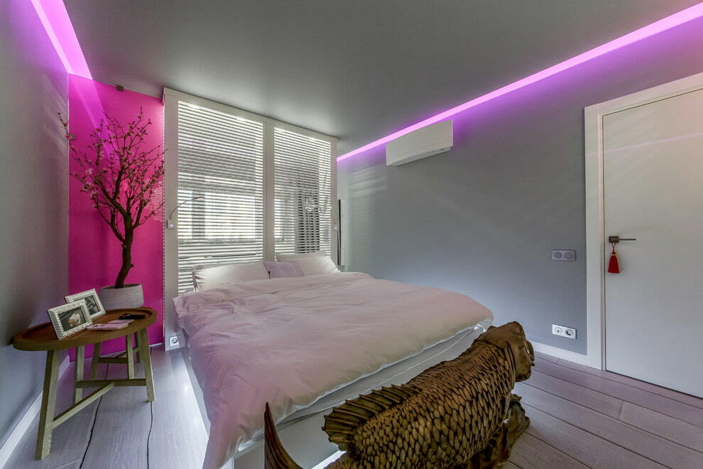 Iluminação rosa de uma parede cinza no quarto