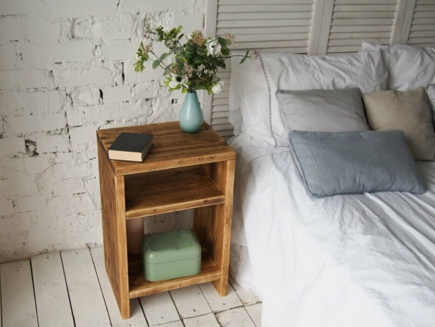 Jednoduchý noční stolek ze dřeva poblíž cihlové zdi