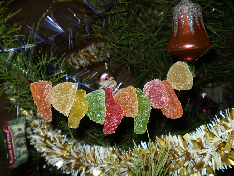 Weihnachtsperlen können aus Angelschnur und Marmelade hergestellt werden. Einfach die Perlen an der Angelschnur auffädeln und an den Baum hängen. Während des Urlaubs trocknet die Marmelade etwas aus, was ihren Geschmack aber kaum beeinträchtigt.