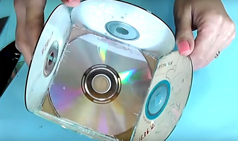 Cole o disco cortado no papelão com uma pistola de cola e use o restante dos discos para montar a caixa. Posicione-os de forma que a superfície com as letras fique dentro da caixa.