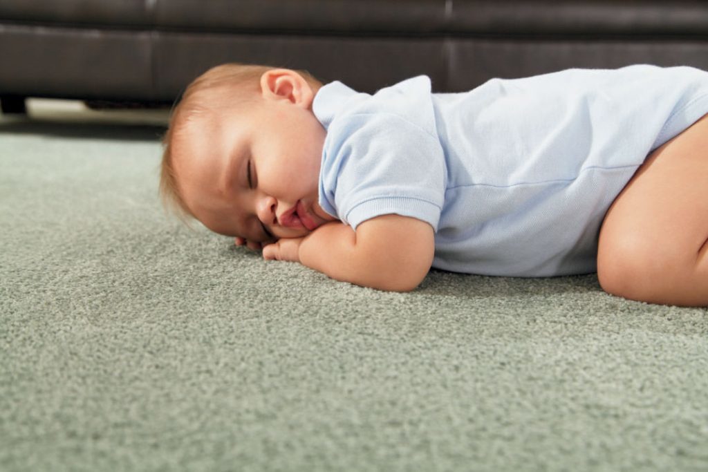 Sleeping bērnu uz paklāja neitrālas krāsas