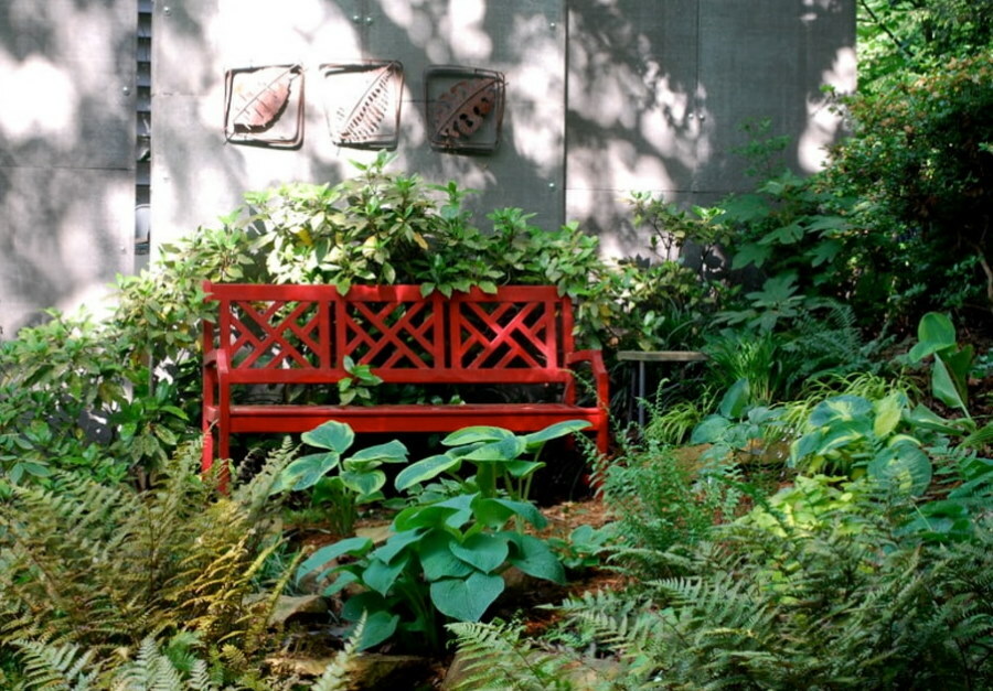 Czerwona ławka wśród zielonych roślin