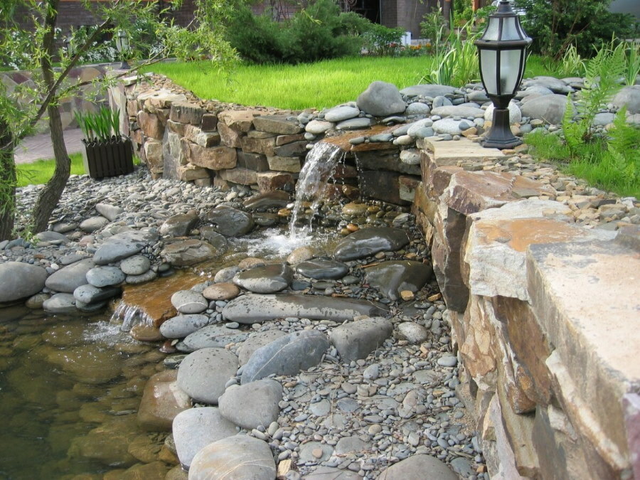 Gartenlaterne in der Nähe eines Wasserfalls aus Steinen