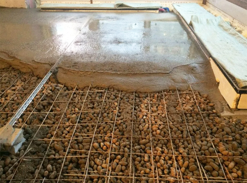 Det är att föredra att använda expanderad lera istället för grus som bas för att gjuta ett betonggolv - på så sätt blir golven mycket varmare. Ett lager av betong - minst 5 cm, ett tunnare golv kan skadas av djur med sina hovar