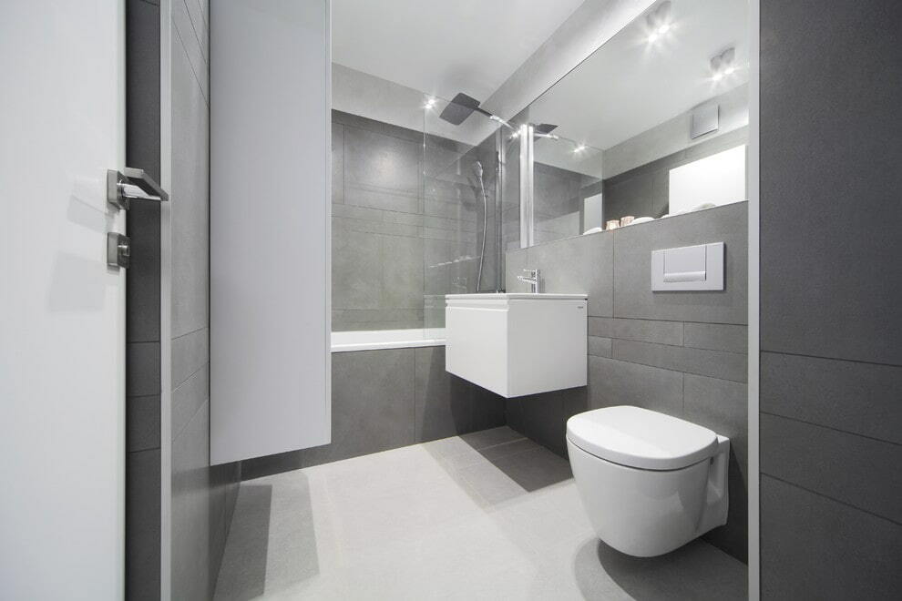 Toilettes suspendues blanches sur un mur de salle de bain gris clair