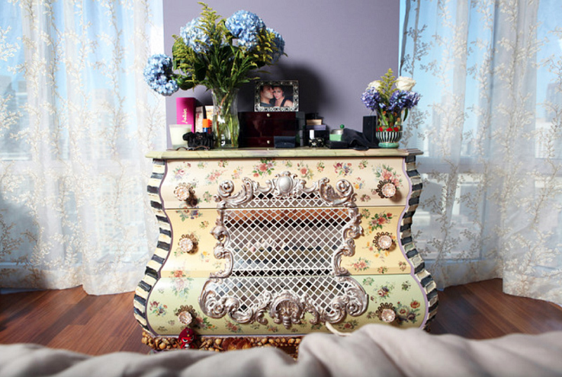 A parte superior da cômoda é adornada com luxuosos arranjos florais e estampas familiares