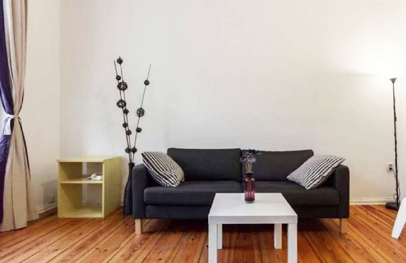 Eine der wenigen Dekorationen im Wohnzimmer ist eine Bodenvase mit einer ungewöhnlichen Anordnung künstlicher Zweige.