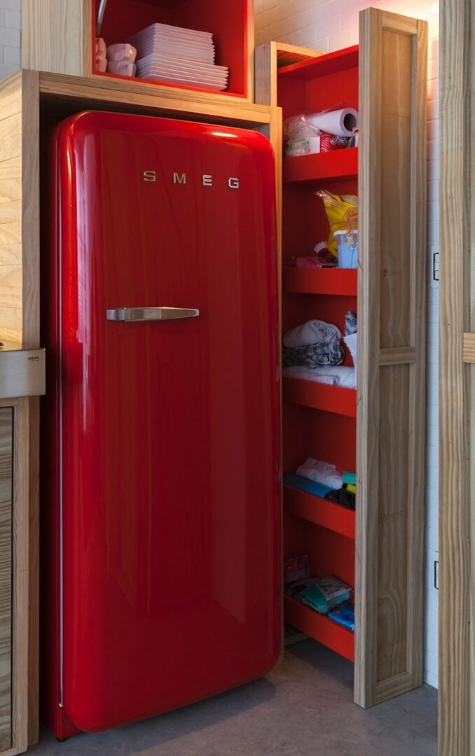 Crveni hladnjak u niši od šperploče