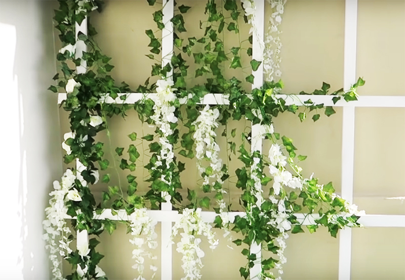If the choice fell on artificial flowers, an imitation of wisteria with its flower clusters will look gorgeous. By the way, it is not at all necessary to screw the grill to the wall - it is enough just to lean it and fix it slightly from below so that it does not accidentally go