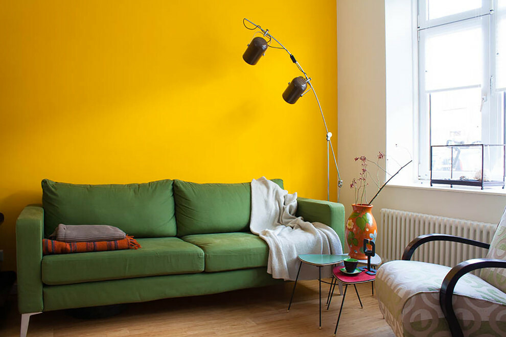 Žalia sofa prie geltonos sienos