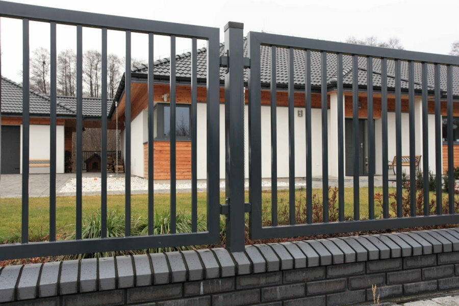 Combined fence made of shaped pipes on a brick base