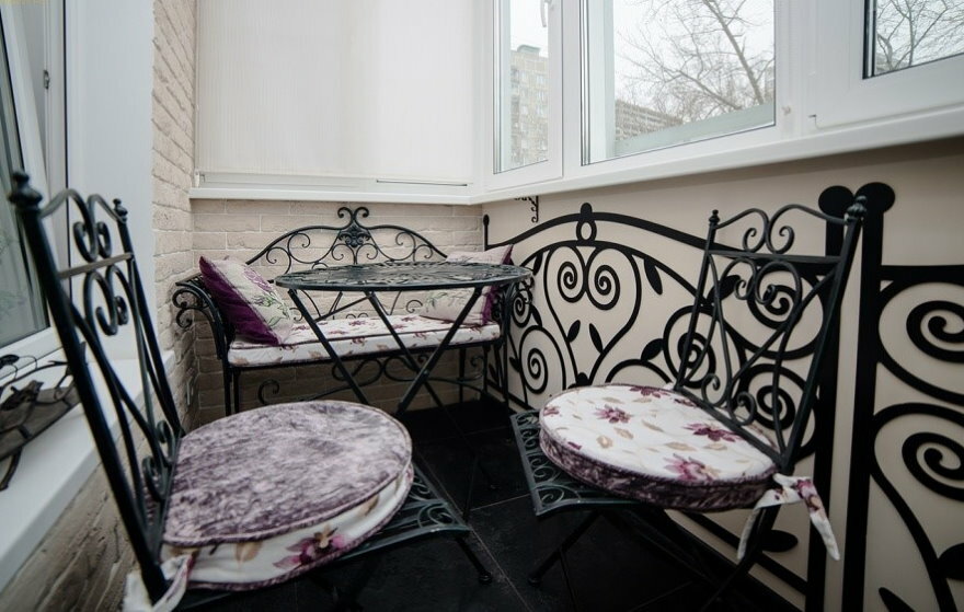 Geschmiedete Stühle auf dem Balkon mit Plastikfenster