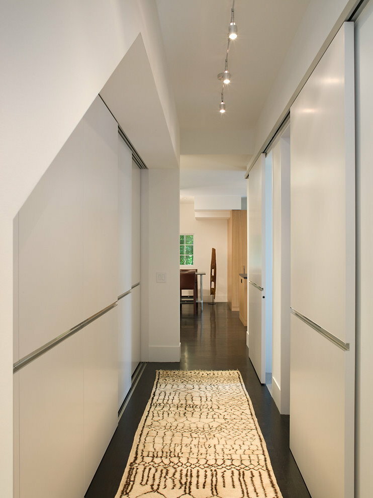 Vit inbyggd garderob i en smal korridor