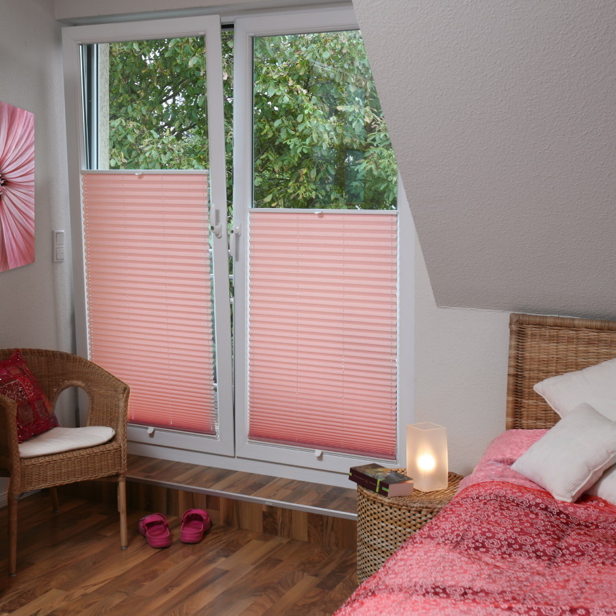 Delicadas cortinas plisadas de color rosa en la habitación de la niña.