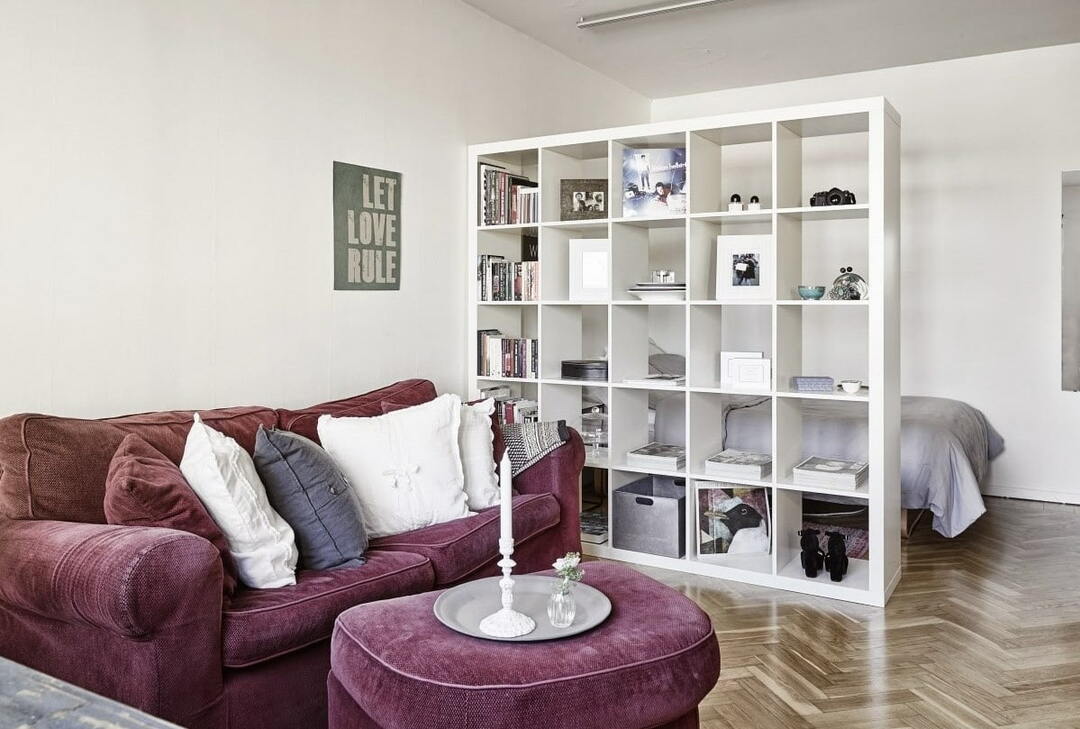 White shelving unit as a partition in a studio apartment
