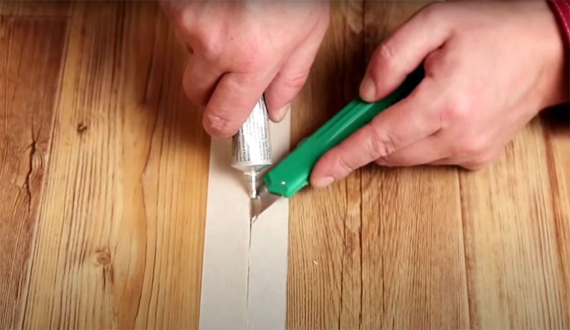 Pry the edge of the linoleum with a thin blade and start moving along the cut, while adding glue to the cut