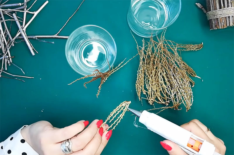 Apply hot glue to the twigs and press them against the glass. It is best to do this at the bottom of the container. Then it will hide under the tape, and the glue will not be noticeable at all.