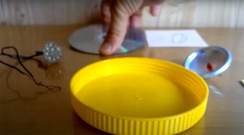 För att deformera en CD till en böjd form behöver du en rund plastplatta med en diameter mindre än själva skivan. Majonnäsburkskruv fungerar bra