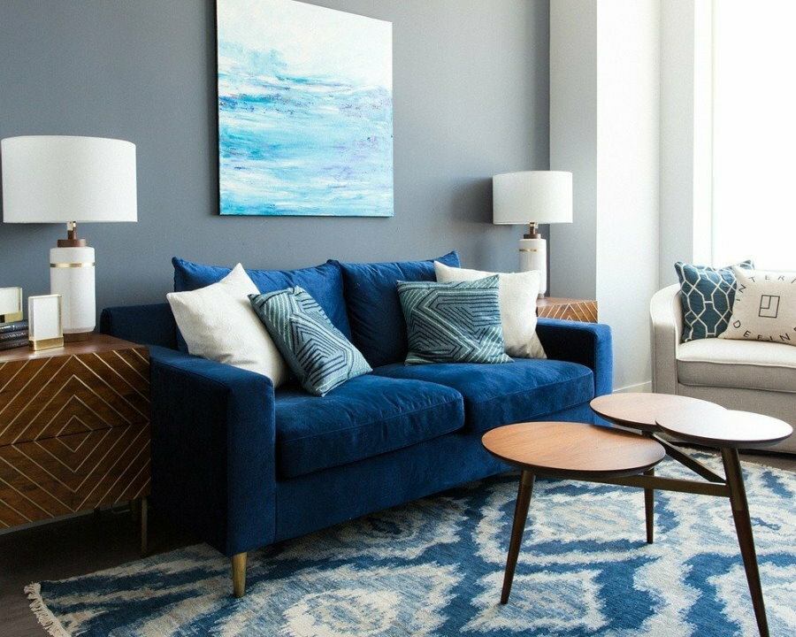 Sienas dekorēšana dzīvojamā istabā virs zilā dīvāna