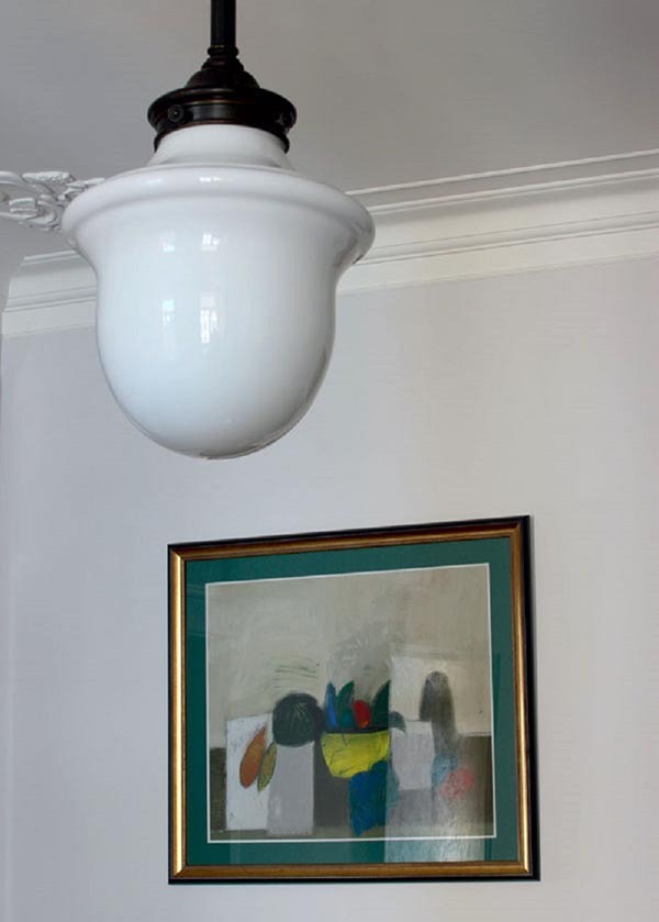 Stuen er opplyst av en uvanlig lampe med en skjerm av hvitt glass i stil med 20 -årene av forrige århundre