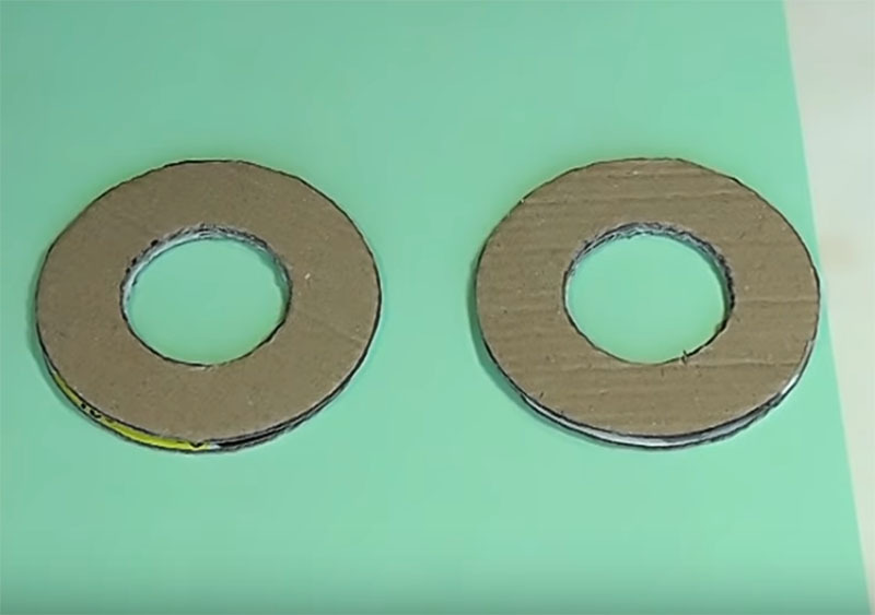 No konteineru kartona izveidojiet divus identiskus gredzenus, kuru diametrs ir aptuveni 10-14 cm