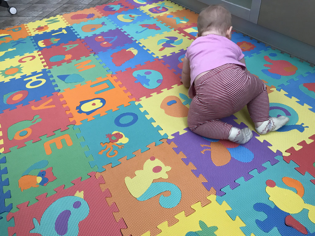 Ein kleines Kind auf der weichen Oberfläche des farbigen Puzzles