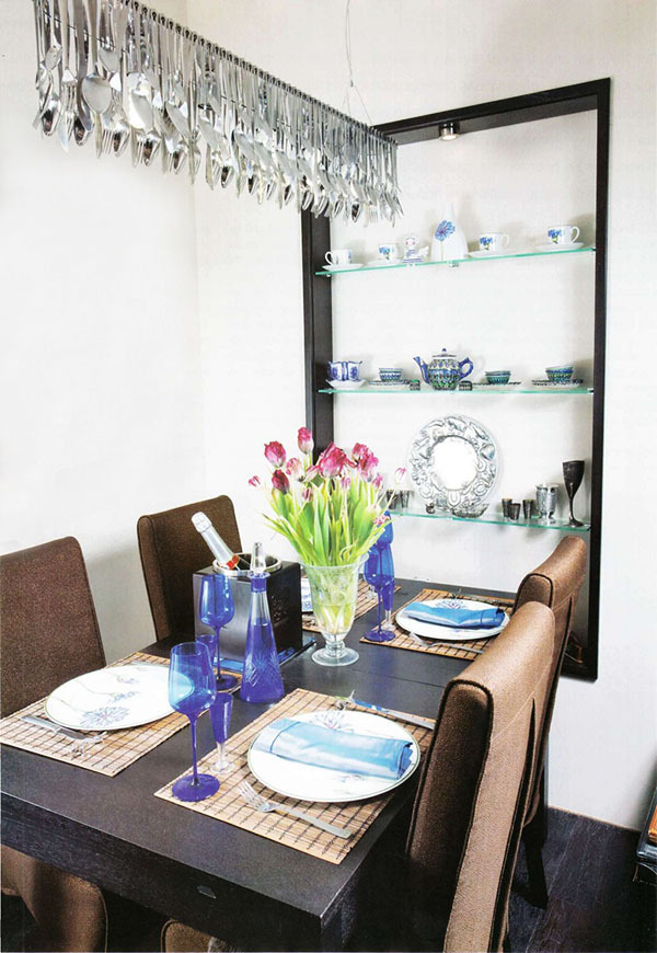 La mesa del comedor se sirve con platos franceses y copas de vino de vidrio de colores.