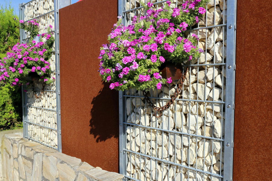 Gabionokból készült kerítés virágzó növényekkel cserépben