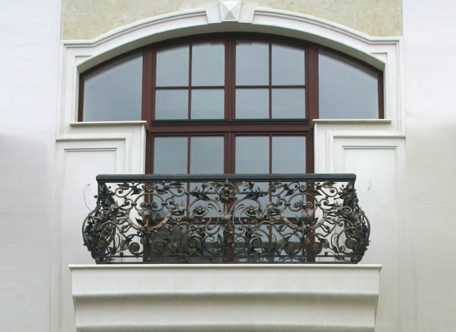 Kaltiniai turėklai namo baltais sienomis balkone