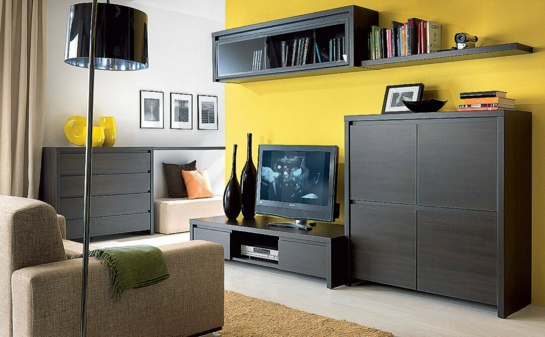 Tmavý nábytek proti žluté zdi obývacího pokoje