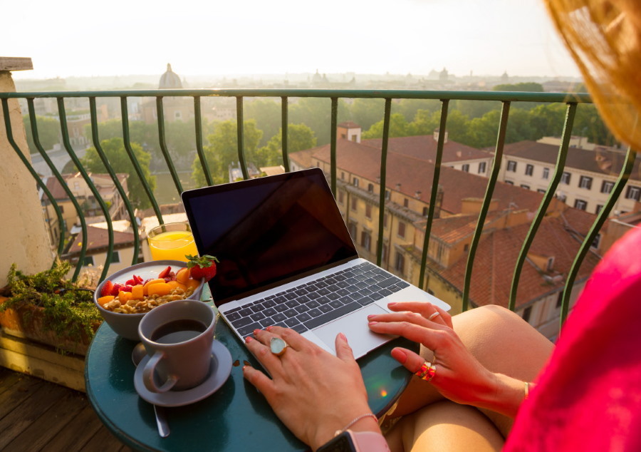 Ragazza con laptop sul balcone aperto