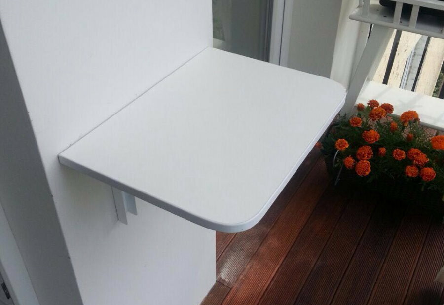 Folding table made of white plastic on the wall of the loggia
