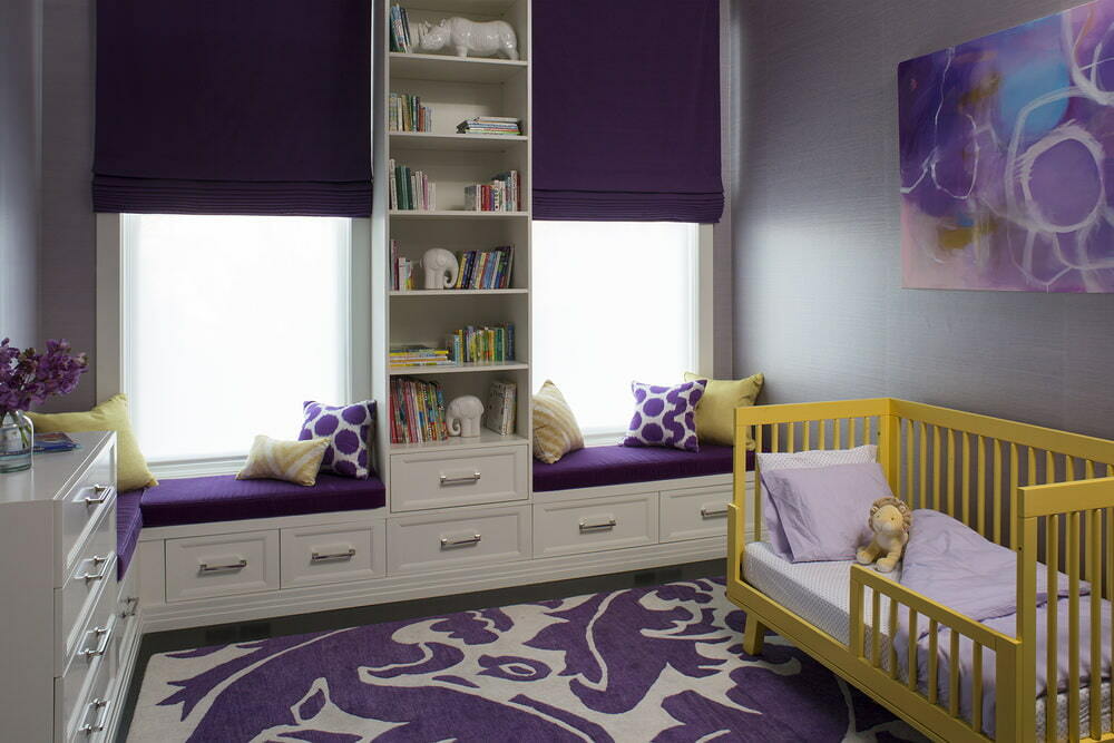 Gelbes Kinderbett für ein Neugeborenes in einem Zimmer mit lila Vorhängen