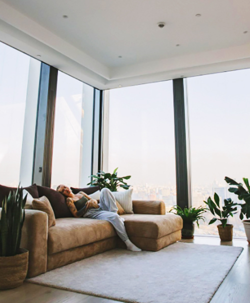 In the corner of the living room, next to the panoramic windows, a beautiful classic beige sofa was placed, which is in good harmony with the surrounding environment