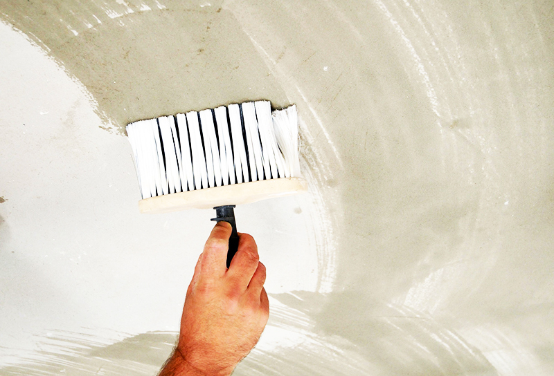 The composition is applied to the concrete base with a brush and a roller.