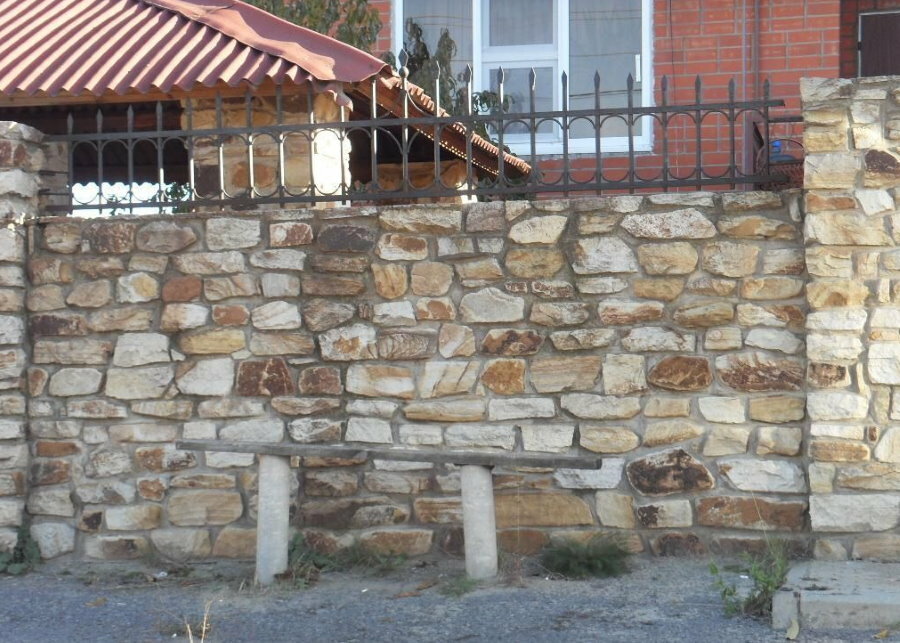 Masywne kamienne ogrodzenie z gruzu przed wiejskim domem