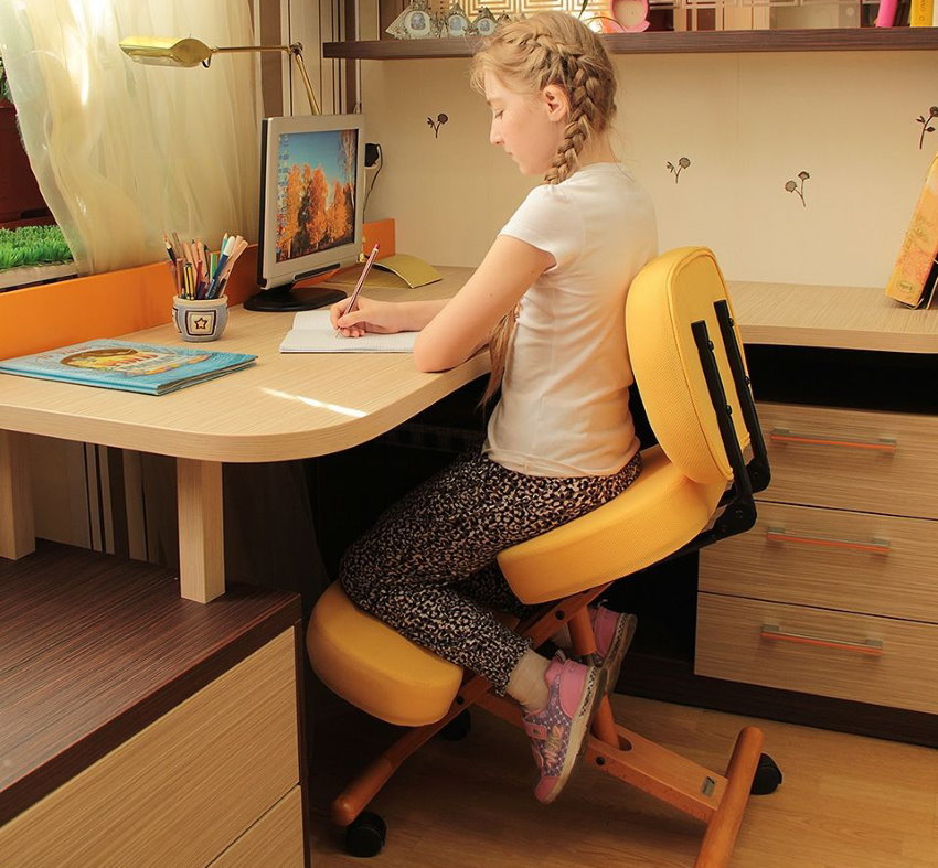 Skolas vecuma meitene par ortopēdisko krēsla
