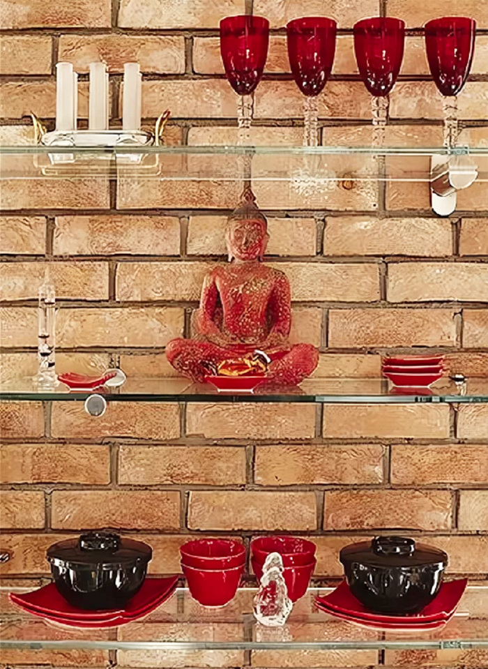 Irina placed dishes and a figurine of a meditating Buddha sitting in the lotus position on glass shelves.
