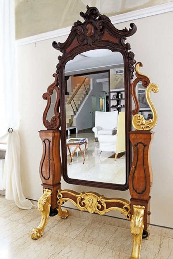 De belangrijkste decoratie van de woonkamer is een antieke spiegel op vergulde gekrulde poten