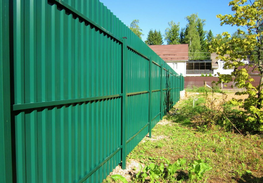 Green fence made of profiled sheet on posts made of shaped pipes