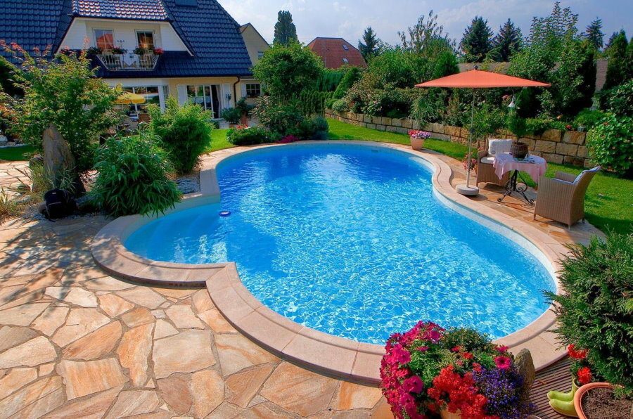 Terrazza in pietra di fronte alla piscina di acqua blu