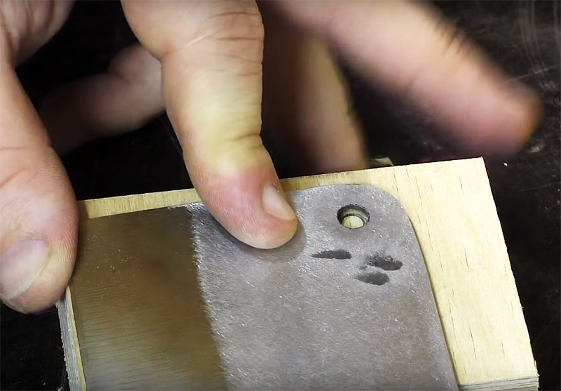 Prepare dos piezas de unos 8 x 10 cm y marque en ellas un lugar para perforar el mismo agujero que en el hacha.