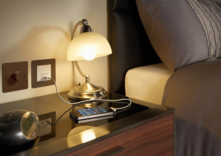 Uma tomada com carregamento USB acima da mesa de cabeceira no quarto