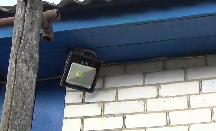 LED prožektorius ant plytų namelio sienos