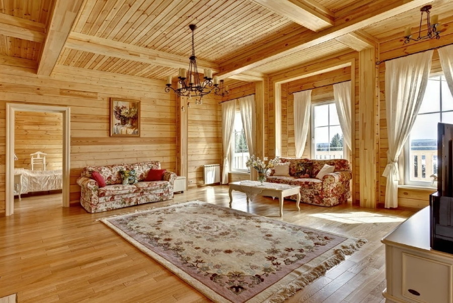 Paklājs koka mājas dzīvojamās istabas interjerā