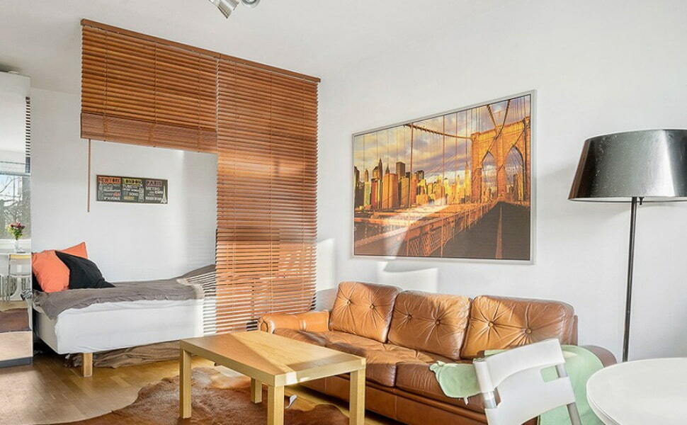 Zonificación del dormitorio-salón con persianas de madera.