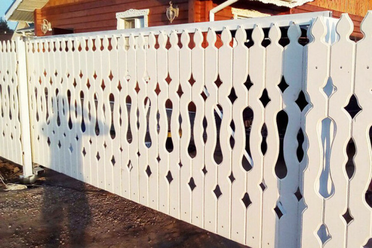 Carved white picket fence in front of the village house