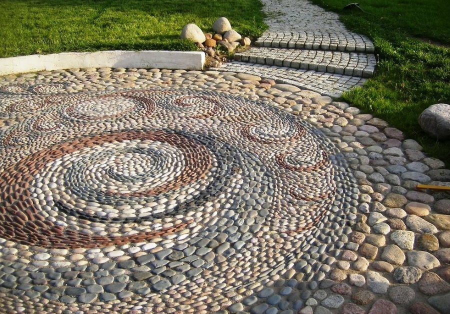 Spiralinis raštas ant įvairių dydžių akmenukų takelio