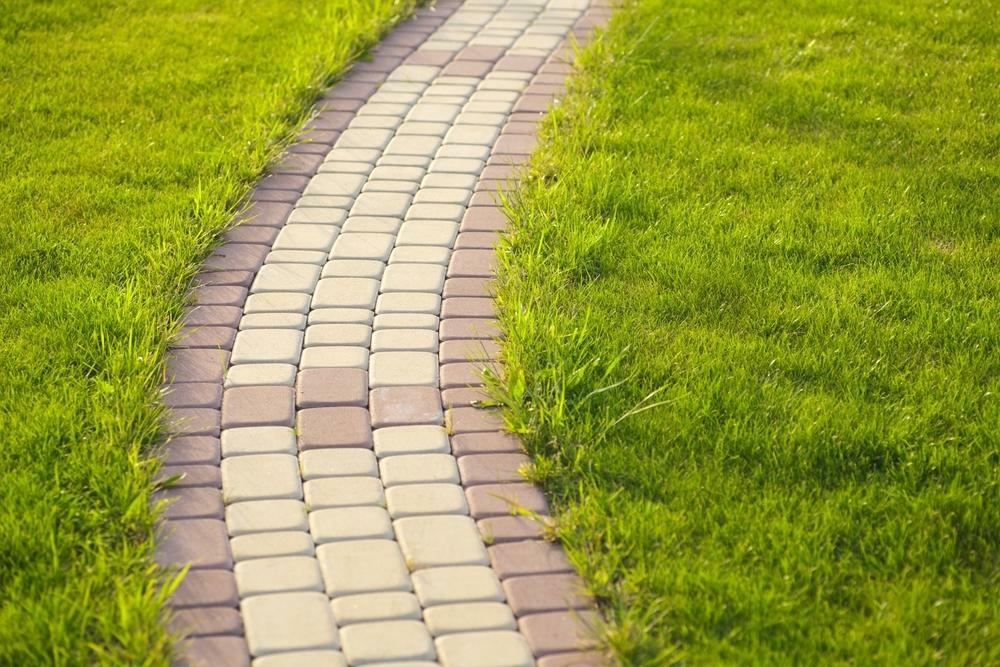 A path made of paving stones of different colors through the lawn